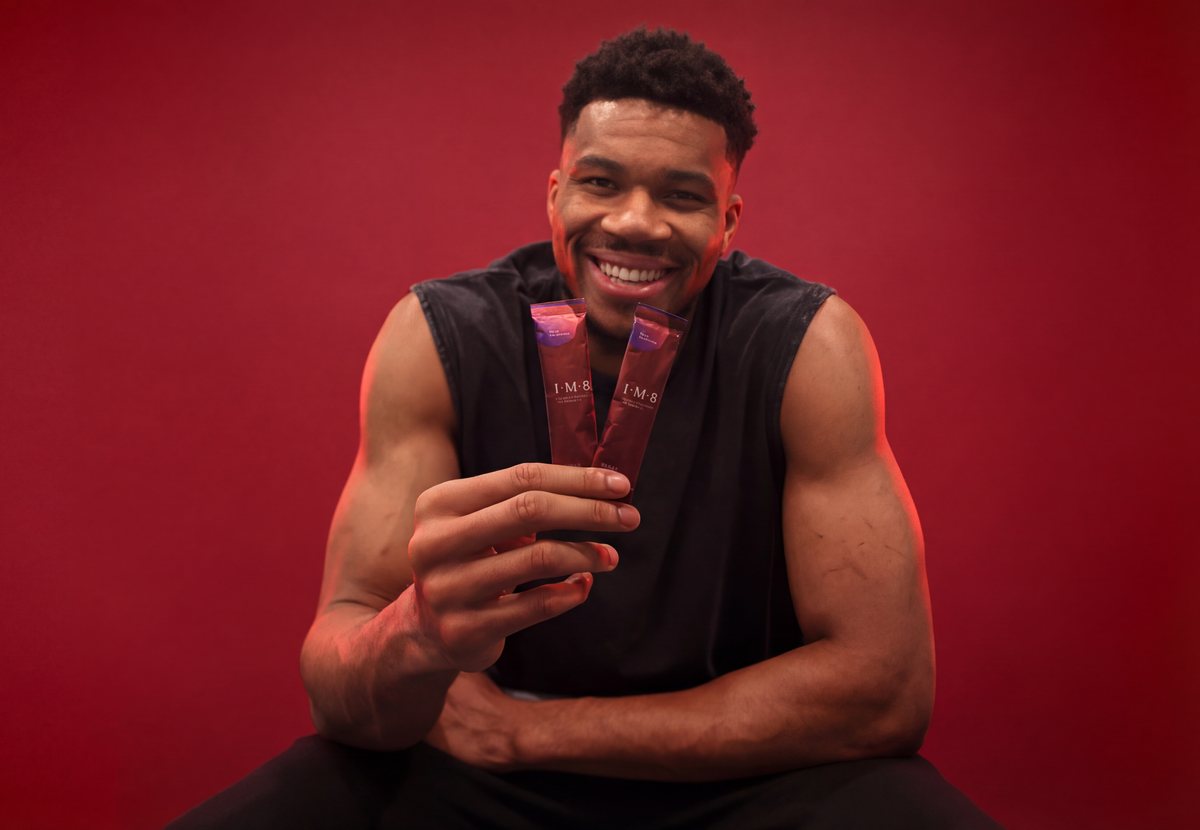 Giannis Antetokounmpo holding two Daily Ultimate Essentials sachets